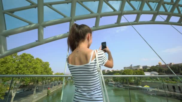Una giovane signora che scatta foto sul ponte sul fiume . — Video Stock