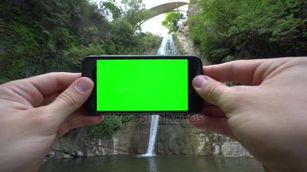 Hände halten ein Telefon mit grünem Bildschirm — Stockvideo
