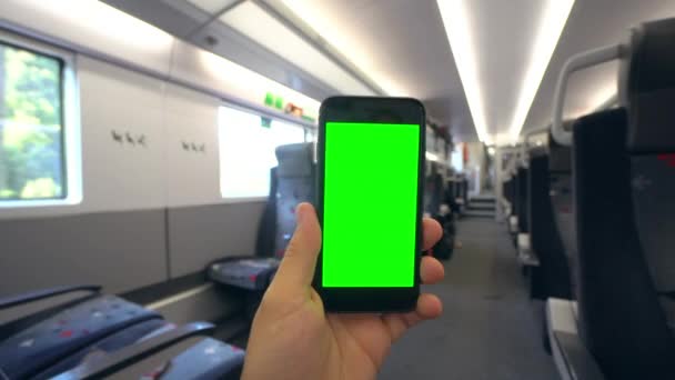 Рука держит телефон с зеленым экраном в поезде — стоковое видео