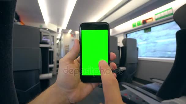 Mão segurando um telefone com uma tela verde no trem — Vídeo de Stock