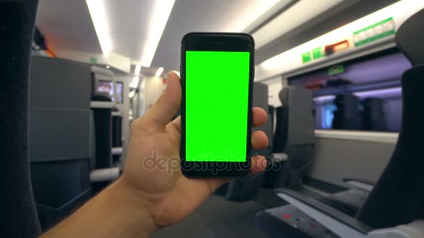 Main tenant un téléphone avec un écran vert dans le train — Video