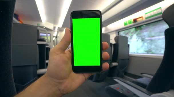 Mão segurando um telefone com uma tela verde no trem — Vídeo de Stock