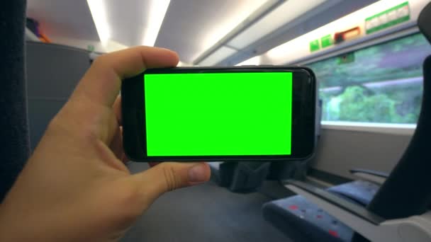 Mano che tiene un telefono con uno schermo verde sul treno — Video Stock