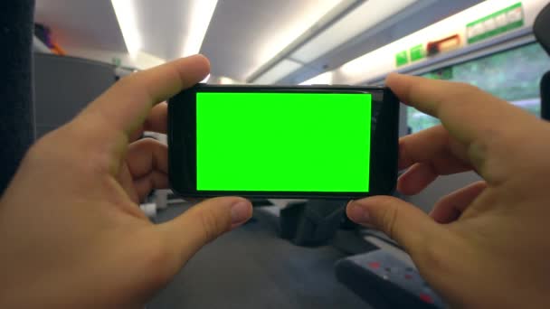 Mãos segurando um telefone com uma tela verde no trem — Vídeo de Stock