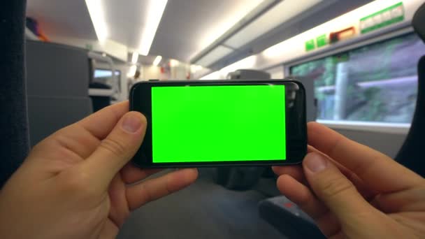 Mãos segurando um telefone com uma tela verde no trem — Vídeo de Stock
