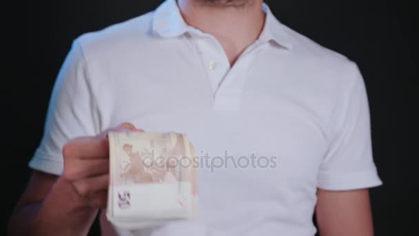 Человек в белой футболке держит наличные — стоковое видео