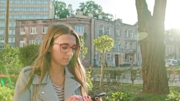 En ung dam promenader och med en Smartphone — Stockvideo