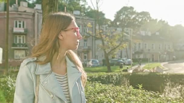 Eine junge Frau, die zu Fuß geht und ein Smartphone benutzt — Stockvideo