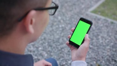 Genç bir adam bir telefon ile yeşil bir ekran kullanma