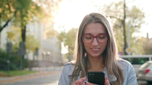 Una giovane signora che utilizza uno smartphone in strada — Video Stock