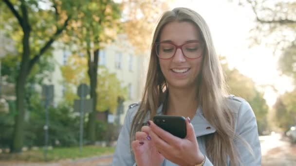 Een jonge dame lopen en met behulp van een Smartphone — Stockvideo