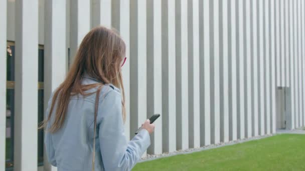 Молода леді ходить і використовує смартфон — стокове відео