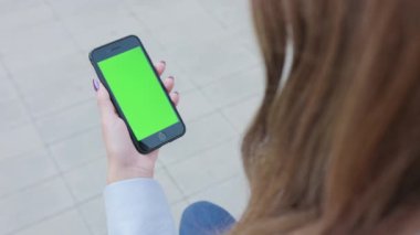 Yeşil bir ekran ile bir telefonu kullanarak bir Bayan