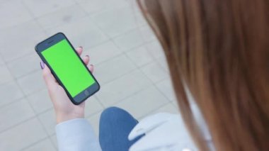 Yeşil bir ekran ile bir telefonu kullanarak bir Bayan