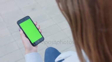 Yeşil bir ekran ile bir telefonu kullanarak bir Bayan