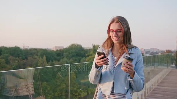 Uma jovem caminhando e usando um telefone ao ar livre — Vídeo de Stock