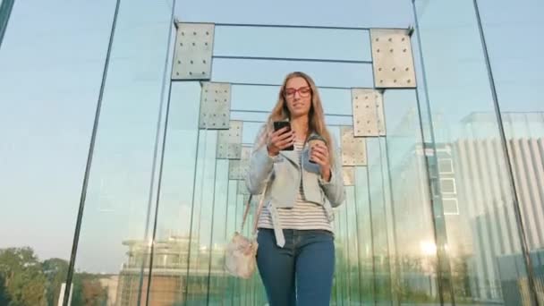 Een jonge dame lopen en met behulp van een telefoon — Stockvideo