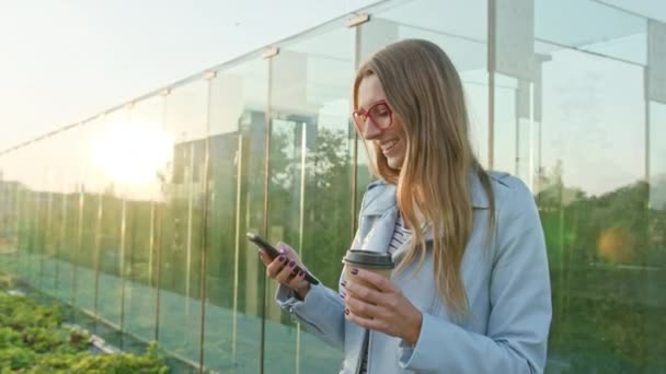 Uma jovem caminhando e usando um telefone ao ar livre — Vídeo de Stock