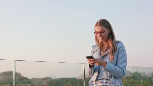 Una joven usando un teléfono inteligente al aire libre — Vídeo de stock