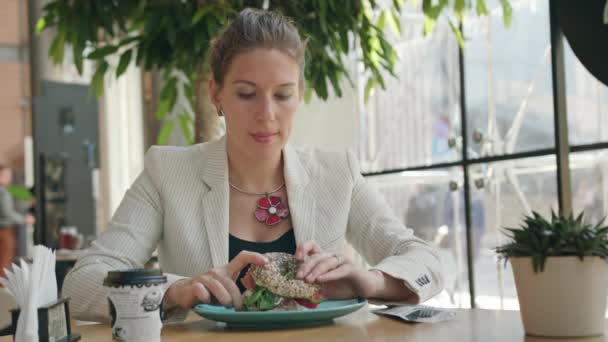 Una giovane signora che mangia panino al caffè — Video Stock