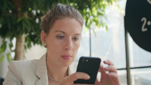 Eine junge Frau mit einem Smartphone im Café — Stockvideo
