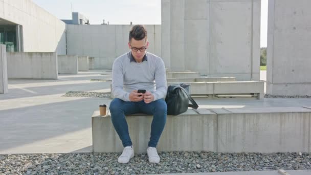 Een jonge Man met behulp van een telefoon buiten — Stockvideo