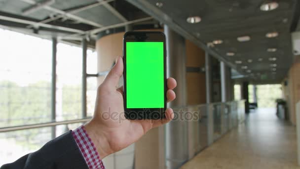 Una mano sosteniendo un teléfono con una pantalla verde — Vídeo de stock