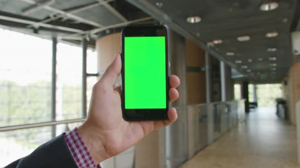 Рука держит телефон с зеленым экраном — стоковое видео