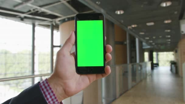 Uma mão segurando um telefone com uma tela verde — Vídeo de Stock