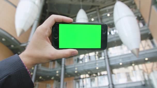 Una mano sosteniendo un teléfono con una pantalla verde — Vídeo de stock