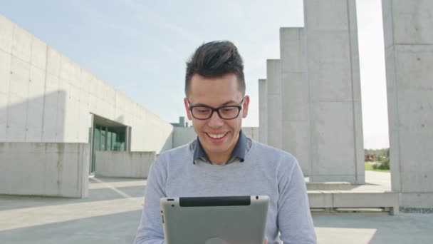 Ένας νεαρός άνδρας, χρησιμοποιώντας ένα Tablet εκτός — Αρχείο Βίντεο