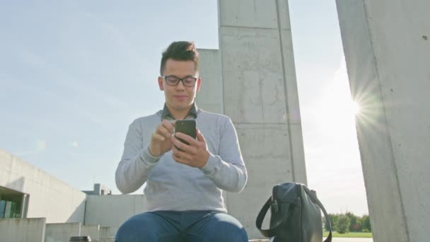 Een jonge Man met behulp van een telefoon buiten — Stockvideo
