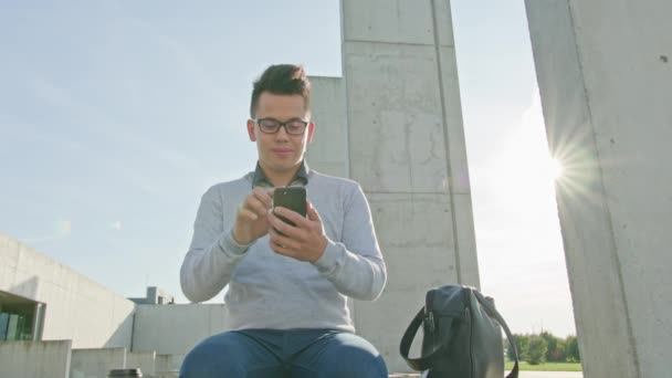 Ein junger Mann, der draußen telefoniert — Stockvideo