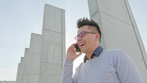 Un jeune homme parle sur un téléphone à l'extérieur — Video