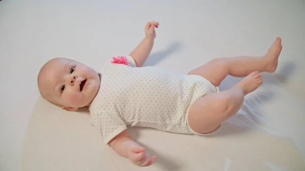 Pequeño bebé curioso está acostado en una manta blanca y mirando a su alrededor — Foto de Stock