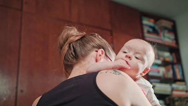 Bebê bonito no ombro da mãe com punho na boca — Fotografia de Stock