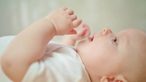 Bebis ligga i sängen på Homeeating sitt Finger och Yawning — Stockfoto