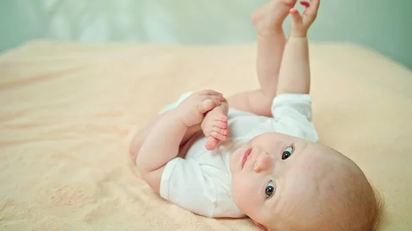 Baby liegt zu Hause im Bett und frisst seinen Fuß — Stockfoto