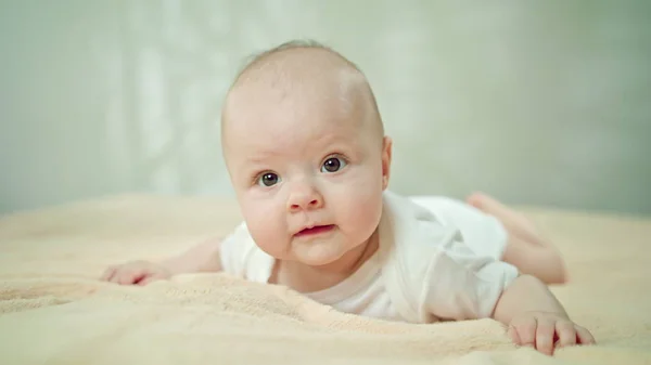 Baby auf Bauch auf weichem Leinen lächelnd — Stockfoto