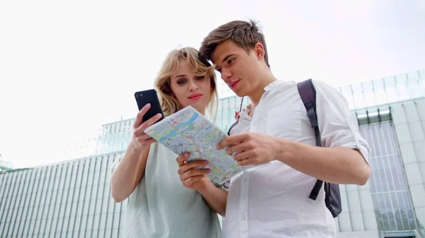 Una joven pareja usando un teléfono móvil al aire libre — Foto de Stock