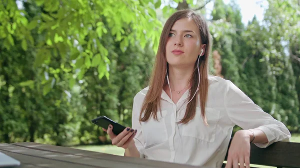 Леди в парке слушает музыку по телефону — стоковое фото