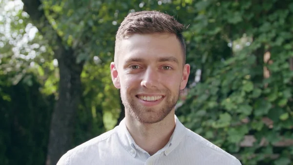 Jongeman kijkt naar de camera en glimlacht — Stockfoto