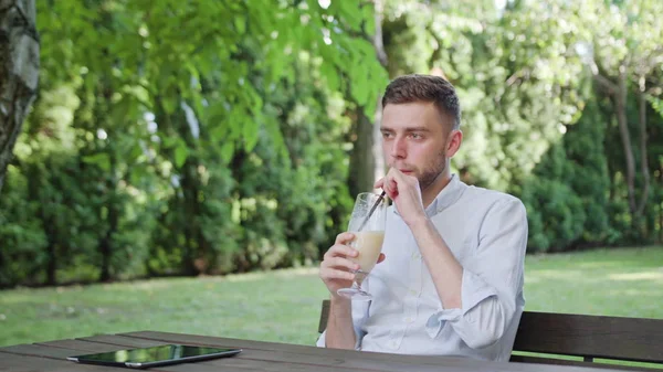 Nuori mies juomassa pirtelöä puistossa — kuvapankkivalokuva