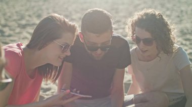 Gençler eğleniyor telefonları kullanarak sahilde