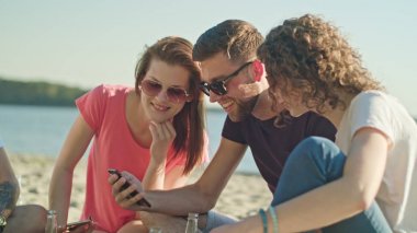 Gençler eğleniyor telefonları kullanarak sahilde