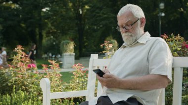 Old Man Using a Phone Outdoors clipart