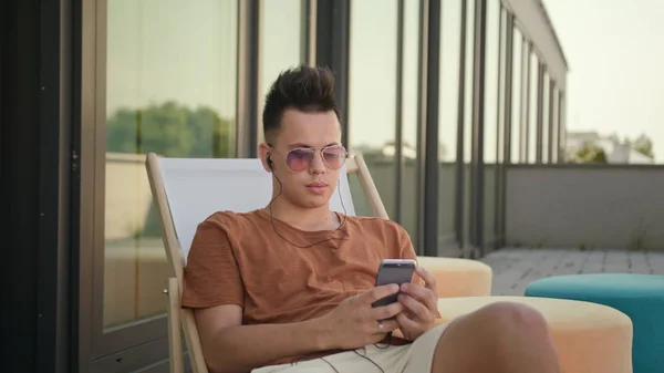 En ung Man med en Smartphone på terrassen. — Stockfoto