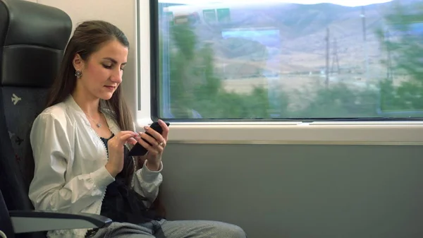 สาวน้อยใช้สมาร์ทโฟนในรถไฟ . — ภาพถ่ายสต็อก