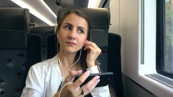 En ung dam med en Smartphone i tåget. — Stockfoto