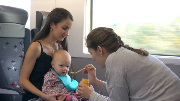 Deux jeunes femmes nourrissant un bébé dans le train — Photo